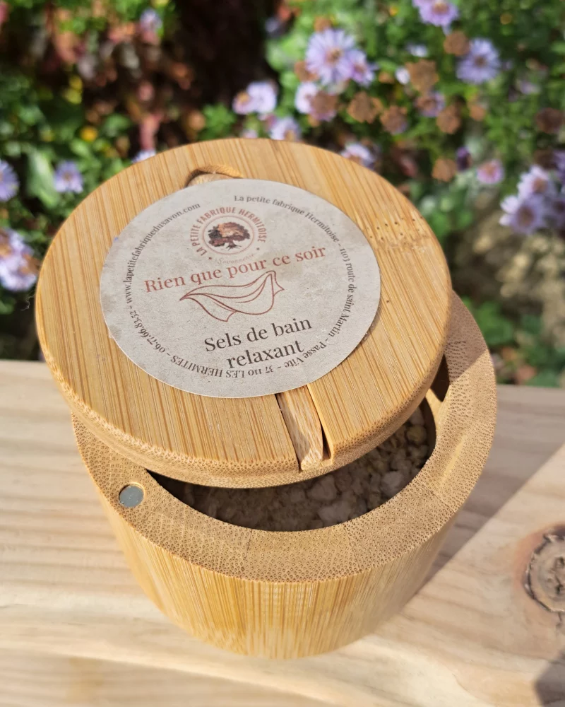 Boite en bambou contenant les sels de bain, sur une planche de bois, fond jardin fleuris